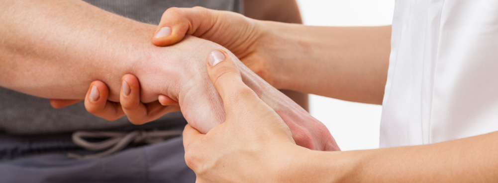 A physiotherapist inspects a patient's wrist for carpal tunnel syndrome